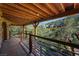 Covered balcony with wooden ceiling and railings overlooking lush mountain landscape at 4888 Snow White Rd, Las Vegas, NV 89124