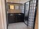 Bathroom featuring black cabinetry, double vanity, and shower with glass block accents at 5748 Spring Ranch Pkwy, Las Vegas, NV 89118