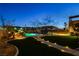 Expansive backyard showcasing a pool with a rock waterfall, a covered lounge, and an illuminated pathway at 6689 Sparks Ave, Las Vegas, NV 89142