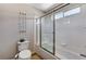 Tiled bathroom features a toilet, bathtub, shower with sliding glass door, and storage shelf at 6689 Sparks Ave, Las Vegas, NV 89142