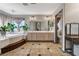 Bright bathroom featuring double sinks, tile flooring, large mirror, soaking tub, and charming accents at 6689 Sparks Ave, Las Vegas, NV 89142