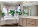 Bright bathroom with a soaking tub, double sinks, decorative curtains, and many potted plants at 6689 Sparks Ave, Las Vegas, NV 89142