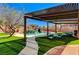 Inviting backyard oasis with a sparkling pool, rock waterfall, pergola, and comfortable lounge seating on lush artificial turf at 6689 Sparks Ave, Las Vegas, NV 89142