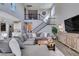 Open-concept living room with a large gray sectional and view of the staircase and second-story balcony at 9519 Chandler Springs Ave, Las Vegas, NV 89148