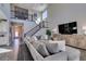 Bright and airy living room with a large sectional sofa and staircase with decorative iron railings at 9519 Chandler Springs Ave, Las Vegas, NV 89148