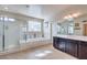 Bright bathroom featuring a glass shower, bathtub and a large mirror at 9655 Shadow Cliff Ave, Las Vegas, NV 89166