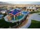 Aerial view showcasing a colorful community playground with shade structure surrounded by green spaces and walkways at 9655 Shadow Cliff Ave, Las Vegas, NV 89166