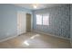 Bedroom with laminate flooring, closet, and a window with blue patterned accent wall at 9870 Giant Steps Ct, Las Vegas, NV 89141