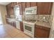 Kitchen features dark cabinets, granite countertops, mosaic tile backsplash and white appliances at 9870 Giant Steps Ct, Las Vegas, NV 89141