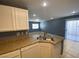 Bright kitchen featuring a stainless steel sink, white cabinets and beige countertops at 10047 Fine Fern St, Las Vegas, NV 89183