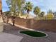 Landscaped backyard featuring artificial grass, decorative rock, block wall, and palm trees at 11009 Royal Highlands St, Las Vegas, NV 89141