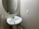 Powder room featuring a pedestal sink, oval mirror, and neutral wall paint at 11009 Royal Highlands St, Las Vegas, NV 89141