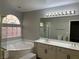 Bathroom with tub, glass block window, and double sink vanity at 11009 Royal Highlands St, Las Vegas, NV 89141
