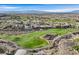 Expansive aerial view of a golf community with lush green fairways and luxury homes against a mountain backdrop at 1320 Enchanted River Dr, Henderson, NV 89012