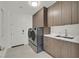 Well-organized laundry room with stainless steel washer/dryer, cabinetry, and utility sink at 1320 Enchanted River Dr, Henderson, NV 89012