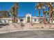 Elegant home exterior featuring desert landscaping, a circular driveway, multiple palms, and a white facade at 1831 Rosemere Ct, Las Vegas, NV 89117