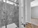Contemporary bathroom with sleek glass-enclosed shower and decorative stone-look tiling, plus wood-look flooring at 380 Baratheon Ave, Las Vegas, NV 89183