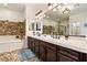 Elegant bathroom featuring double sinks, a soaking tub, a glass shower and stylish fixtures at 3823 Chapels Royal St, Laughlin, NV 89029