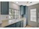 The galley kitchen features blue cabinets, white countertops and a stainless steel sink below the window at 4718 Nara Vista Way # 101, Las Vegas, NV 89103