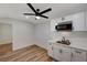View of the kitchenette with white cabinetry, wood-look flooring, ceiling fan, and stainless steel microwave at 4804 El Tesoro Ave, Las Vegas, NV 89121