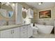 Bathroom featuring double sinks, white cabinets, soaking tub and decorative art at 602 Paloma Dr, Boulder City, NV 89005