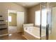 Bathroom with a large tub, a window with blinds, and an open doorway to another room at 629 Bright Lights Ave, North Las Vegas, NV 89031