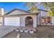 Welcoming facade showcasing a tidy front yard, an arched entryway, and a two-car garage at 6741 Bonillo Dr, Las Vegas, NV 89103