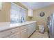 Bright laundry room with white cabinetry, stainless steel washer/dryer, and a view from a large window at 7600 Pleasant Colony Ct, Las Vegas, NV 89131