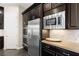 Kitchen boasts stainless steel appliances, including oven and microwave, with beautiful dark wood cabinetry and a mosaic backsplash at 7763 Brisk Ocean Ave, Las Vegas, NV 89178