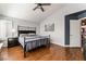 Bright bedroom featuring hard wood floors, a ceiling fan, and large bed frame with dark metal accents at 7837 Silver Plateau Ave, Las Vegas, NV 89128