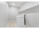 Bright laundry room features a white washer and dryer, neutral walls, and a convenient shelving unit above at 10785 Wild Parsley Ave, Las Vegas, NV 89129