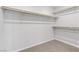 Bright, neutral walk-in closet with multiple levels of shelving, storage rods and neutral carpeting at 10785 Wild Parsley Ave, Las Vegas, NV 89129