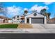 Charming one-story home featuring a gray garage door, white exterior, and well-maintained yard at 1905 Joella St, Las Vegas, NV 89108