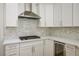 Modern kitchen with a stainless steel vent hood, gas cooktop, and white marble backsplash at 2265 Lauren Dr, Las Vegas, NV 89134