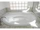 Jetted white soaking tub featuring tile surround, and glass block window at 2265 Lauren Dr, Las Vegas, NV 89134