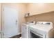 Bright laundry room features a modern washer and dryer with a shelf above and a white door at 2392 Mystic Star St, Henderson, NV 89044