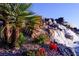 Beautiful rock waterfall feature in the community with native flowers and fauna on a clear day at 2921 Hayden Creek Ter, Henderson, NV 89052