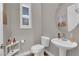 Neutral powder room featuring a pedestal sink, toilet, window with shutters, and stylish decor at 41 Via Verso Lago, Henderson, NV 89011