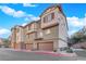 View of townhome featuring multiple garage doors, brick accents, and a clean sidewalk at 41 Via Verso Lago, Henderson, NV 89011