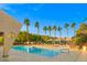 Resort-style pool area with several palm trees, shaded lounge areas, and a clear blue sky at 5060 Indian River Dr # 382, Las Vegas, NV 89103