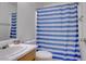 Bathroom featuring a toilet, sink with cabinet, mirror, and blue and white striped shower curtain at 5541 Ramirez St, North Las Vegas, NV 89031