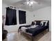 Spacious bedroom with ceiling fan, carpet, bed with black duvet and pillows with portraits and dark curtains at 5541 Ramirez St, North Las Vegas, NV 89031