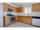 Bright kitchen showcasing stainless steel appliances, including oven and microwave, along with wood cabinets and tile flooring at 5541 Ramirez St, North Las Vegas, NV 89031