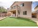 Backyard with artificial grass, covered patio, and a balcony above at 6938 Silk Oak Ct, Las Vegas, NV 89148