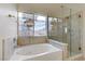 Bright bathroom featuring a corner tub with jets, a large window, and a glass-enclosed shower at 6938 Silk Oak Ct, Las Vegas, NV 89148