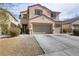 Two-story home with a three car garage, desert landscaping, and neutral paint at 6938 Silk Oak Ct, Las Vegas, NV 89148