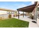 Inviting backyard with artificial grass, a covered patio, and partial view of the pool at 7165 N Grand Canyon Dr, Las Vegas, NV 89149