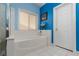 Bright bathroom featuring a large tub, window, and white tiled flooring at 8213 Cabin Springs Ave, Las Vegas, NV 89131