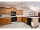 Well-lit kitchen featuring oak cabinets, a black oven, and tiled flooring with a view to the living room at 8213 Cabin Springs Ave, Las Vegas, NV 89131