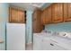 Well-equipped laundry room with washer, dryer, refrigerator, and ample wooden cabinet storage at 8213 Cabin Springs Ave, Las Vegas, NV 89131